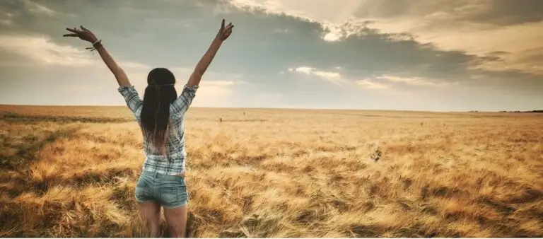 woman raising her arms feeling worthy of the sun on her face