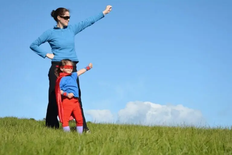 courageous parent and girl standing in the grass posing like a superhero