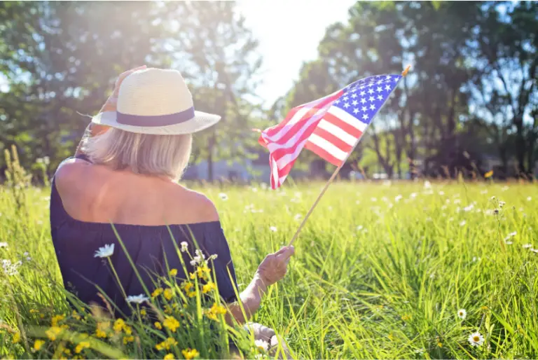 woman in grass waving American flag