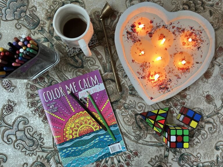 Lit candle with coloring books and other items to convey relaxation