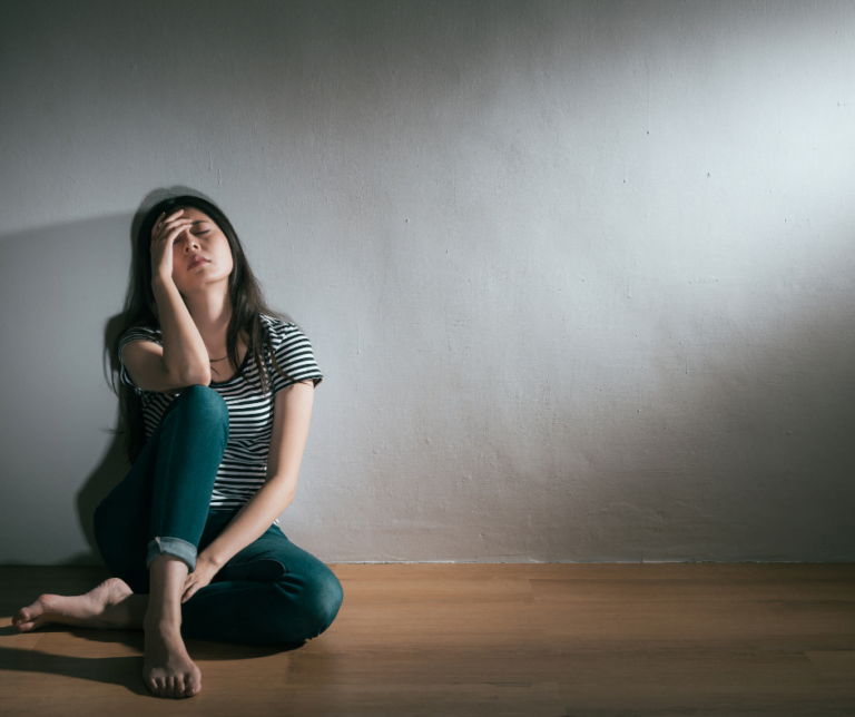 a woman sitting on the floor with her hand on her face looking sad